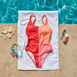 Une sc&egrave;ne estivale lumineuse au bord de la piscine avec un maillot de bain de haute qualit&eacute; soigneusement pos&eacute; &agrave; plat sur une serviette blanche &agrave; l’ombre. A proximit&eacute; se trouvent de l'eau douce, de la cr&egrave;me solaire et des lunettes de natation. Le maillot de bain a l'air vibrant et bien entretenu.jpg